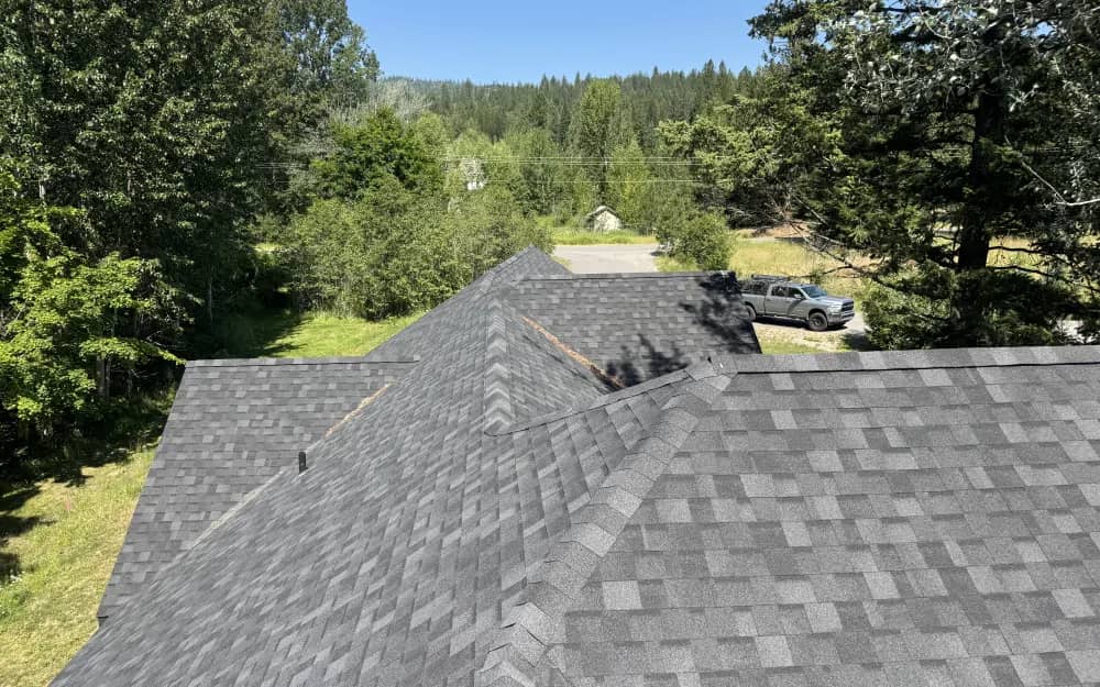 Elevated view of gray asphalt shingles and intersecting roof planes near Cocolalla, Idaho