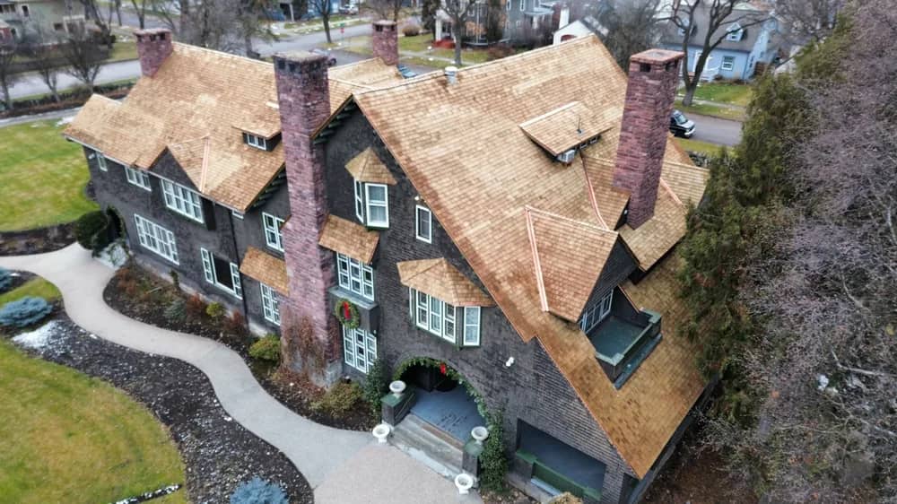 Cedar shingle roof chimney-side aerial view Aerial view across a cedar shingle roof with brick chimneys and intersecting roof planes
